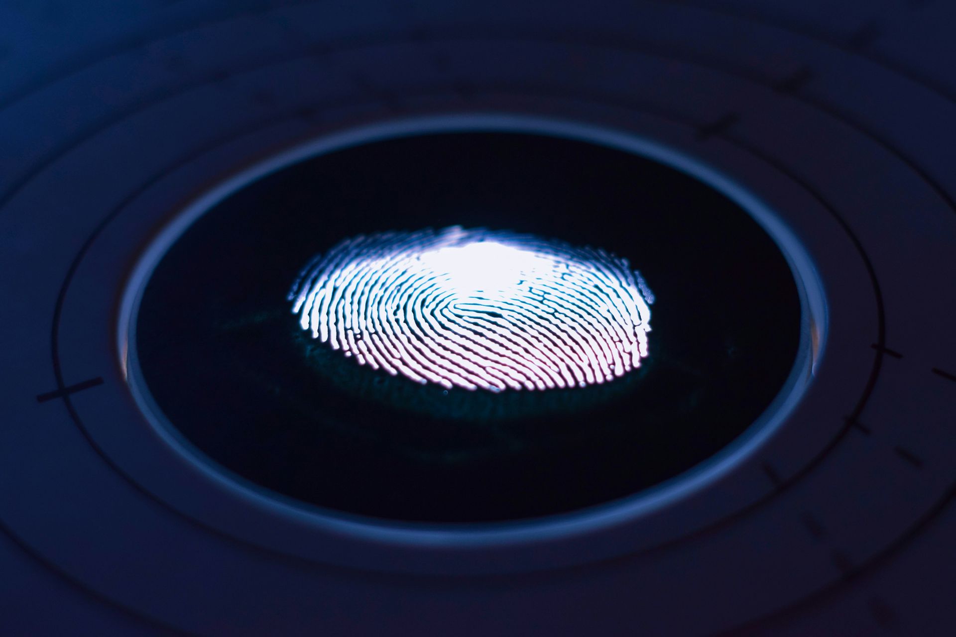 A glowing fingerprint on a dark circular scanner surface with concentric lines